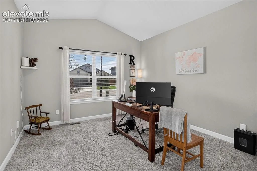 Bright flex room used as a home office with vaulted ceiling