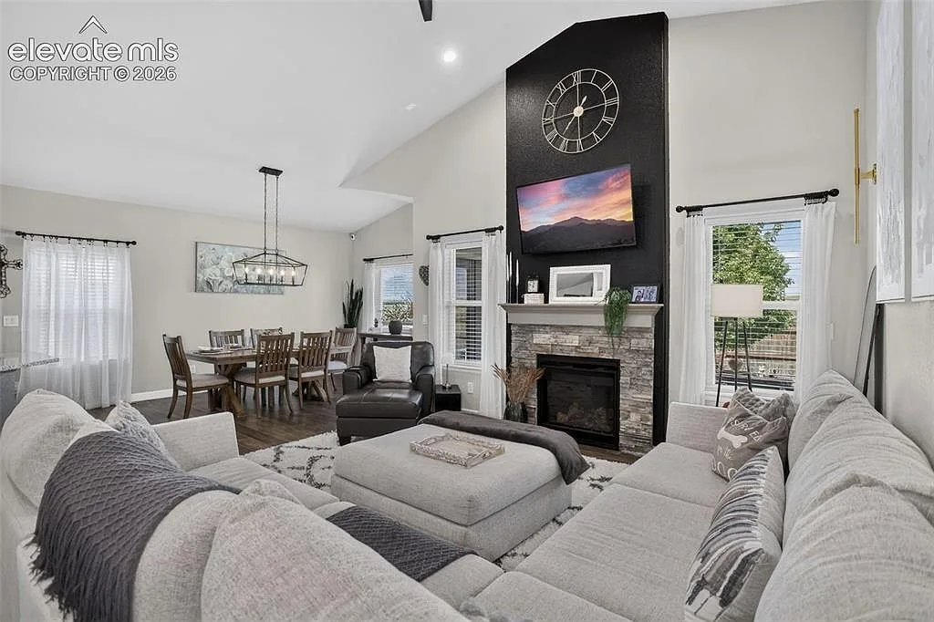 Open concept living and dining room with a stone faced fireplace at 10988 Tarbell Dr
