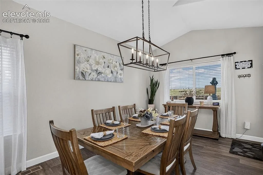 Dining room with wood flooring under a vaulted ceiling