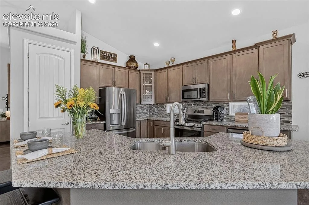 Kitchen island and sink with granite counters and wood cabinetry