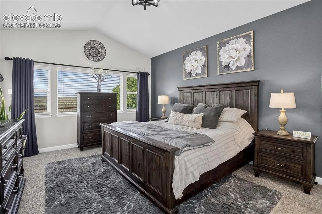 Primary bedroom with vaulted ceiling and charcoal accent wall