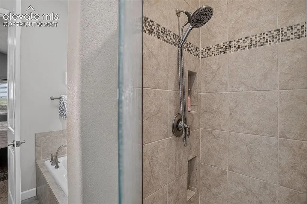 Primary bathroom tile walk-in shower with built in shelving