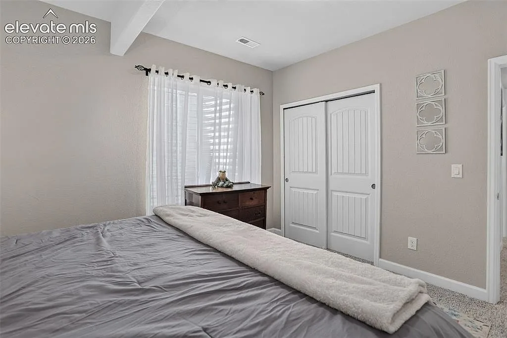 Secondary bedroom with sliding closet doors and a window