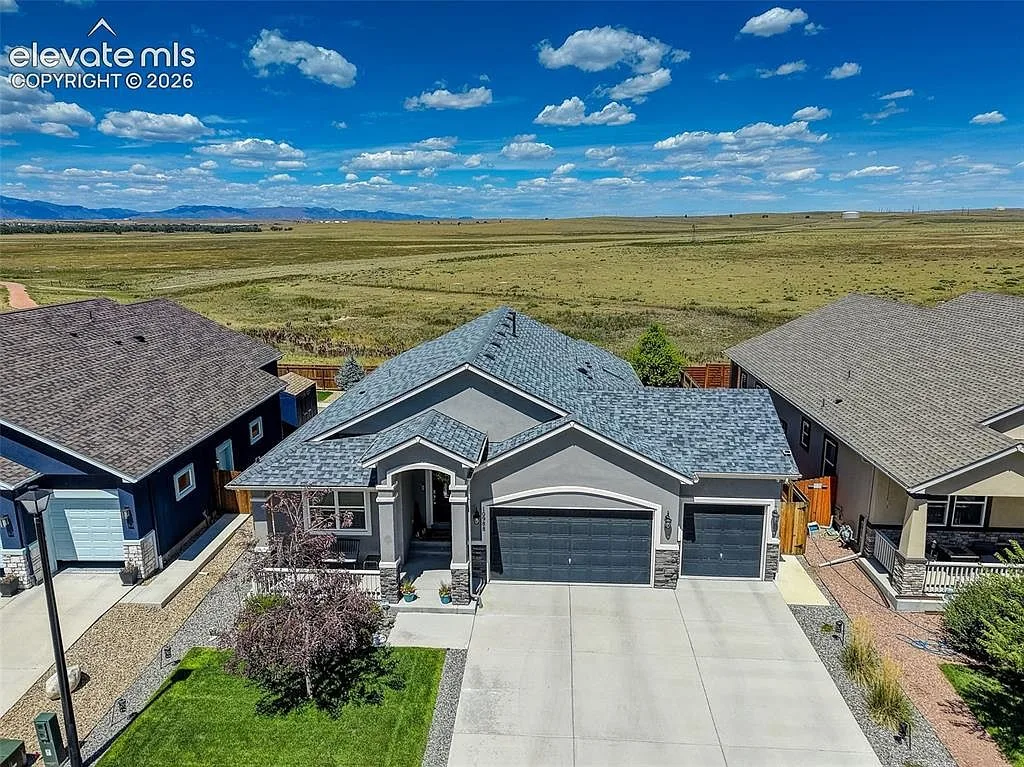 Aerial view of 10988 Tarbell Dr, a grey stucco and stone ranch home backing to open space in Lorson Ranch