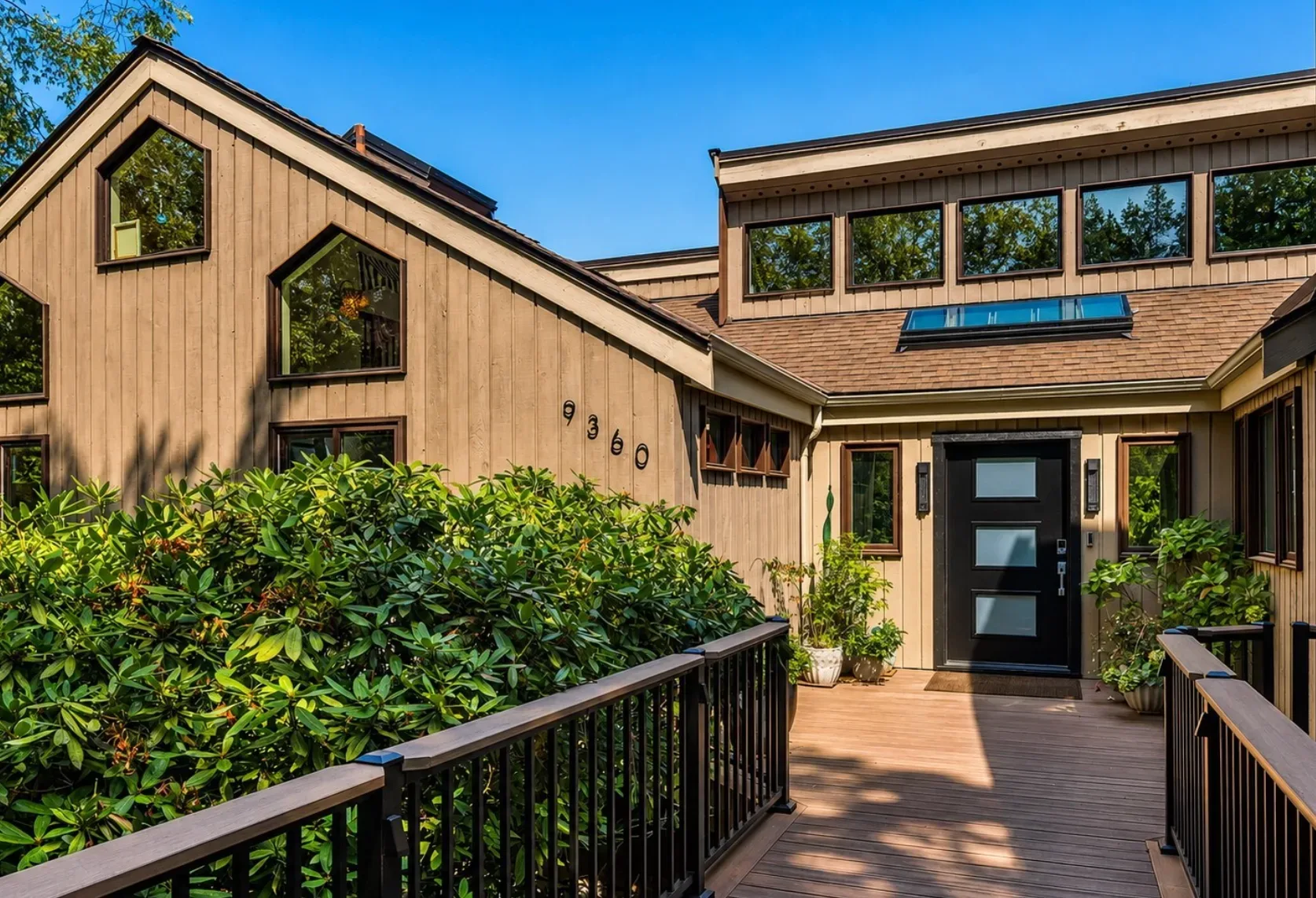 The contemporary front facade of a Mercerwood Drive home on Mercer Island, with a raised wooden walkway and walls of glass