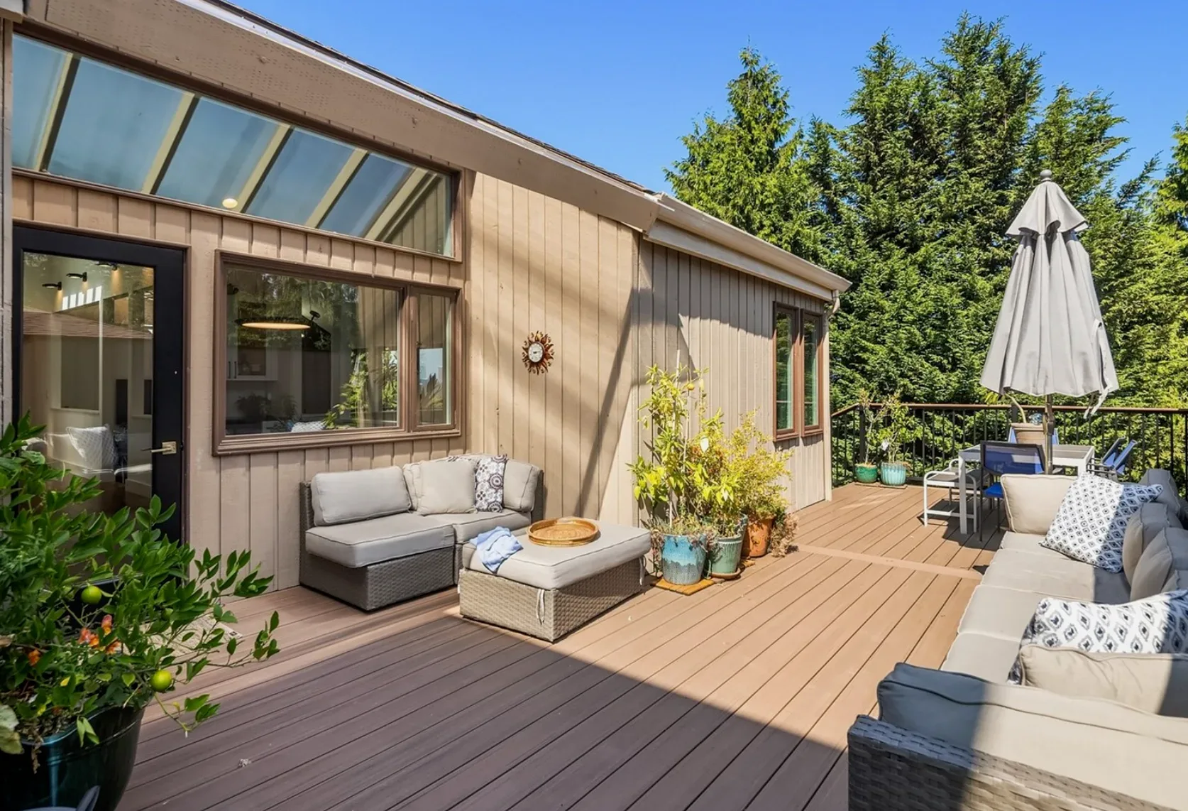 Backyard deck with large windows and glass doors overlooking a private, fenced, grassy yard with mature trees