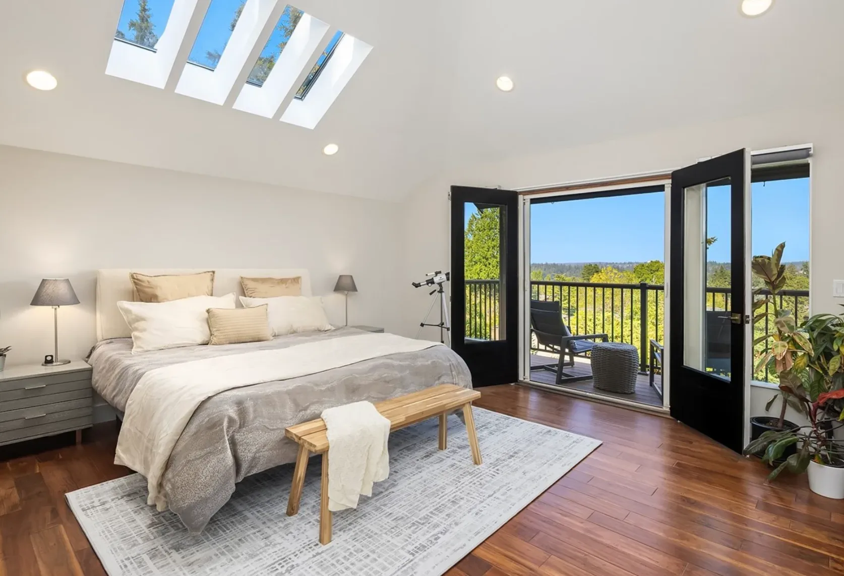 Oversized primary bedroom with vaulted skylights and French doors opening to a private balcony