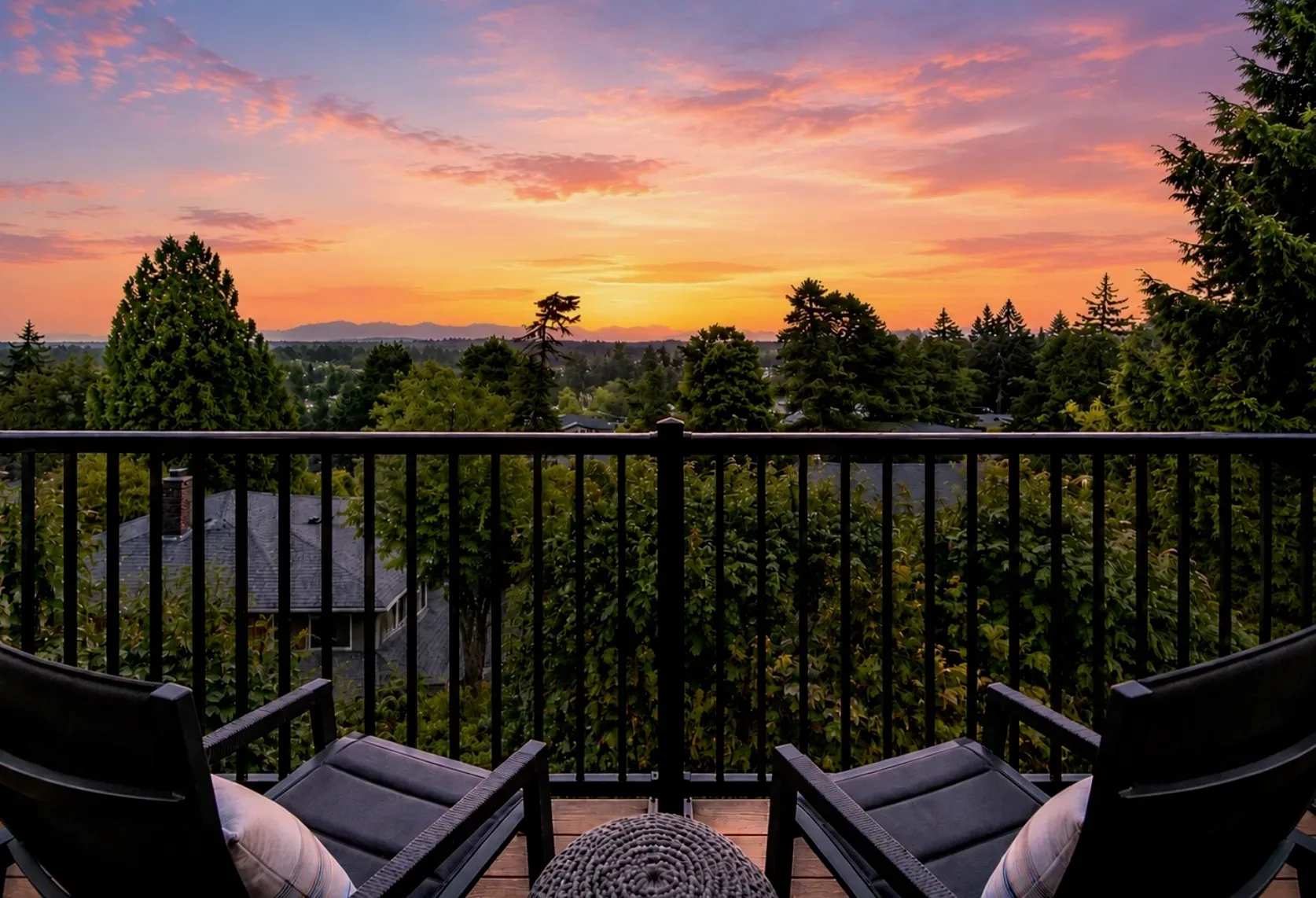 Elevated view from the deck over the treetops at sunset, with soft pink and orange light across the neighborhood