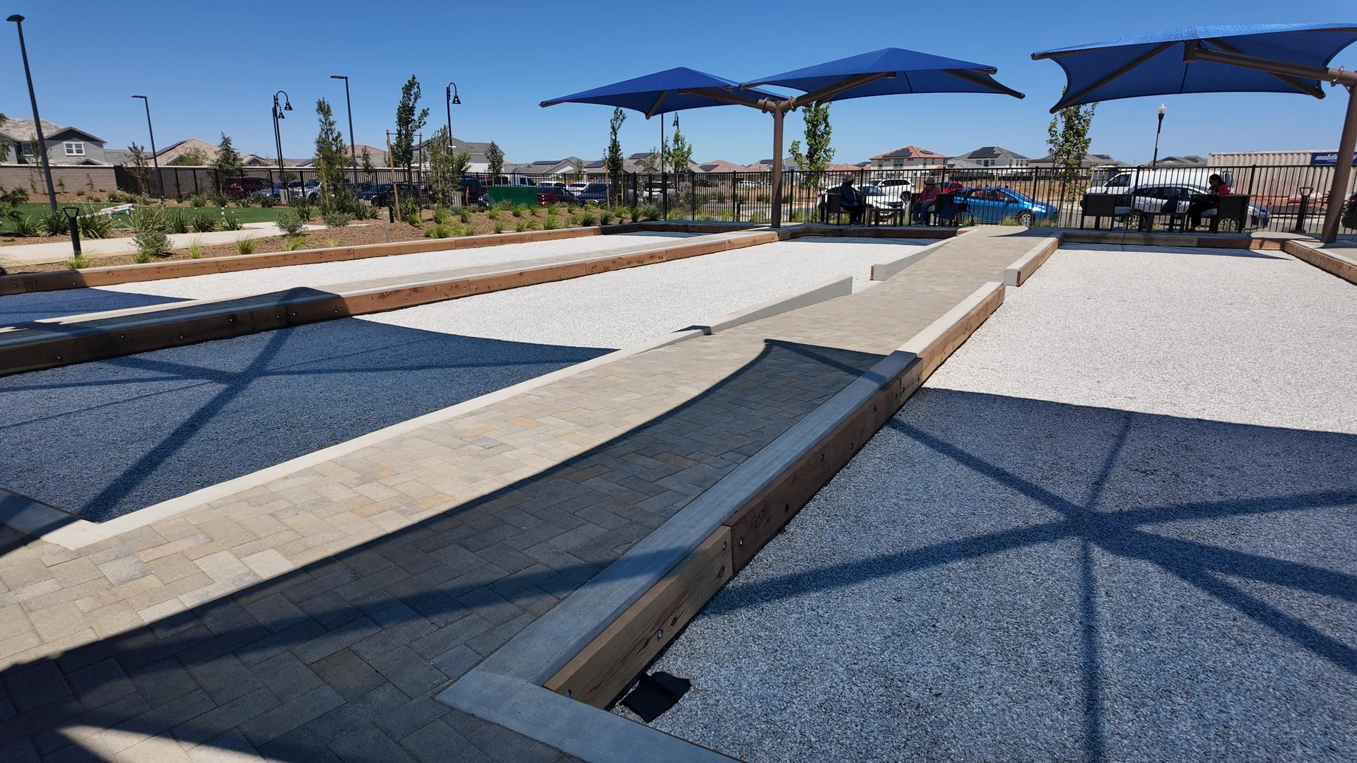 Bocce ball courts at Esplanade at Madeira Ranch, with green turf courts, stone borders, and shade umbrellas beside the Lodge grounds.
