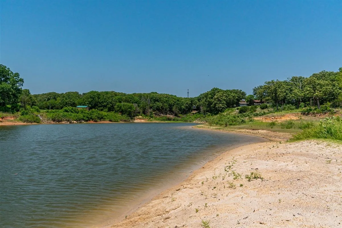 Sandy shoreline and calm water of Lake Texoma stretching toward the horizon