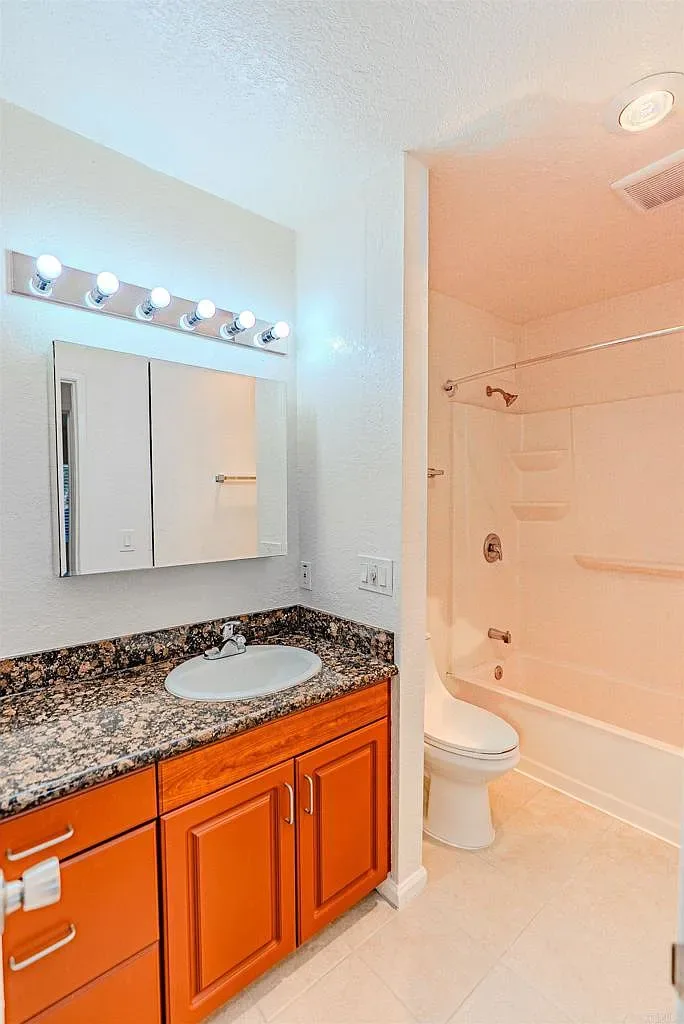 Bathroom with granite-topped vanity and tub at 1085 12th St Unit F