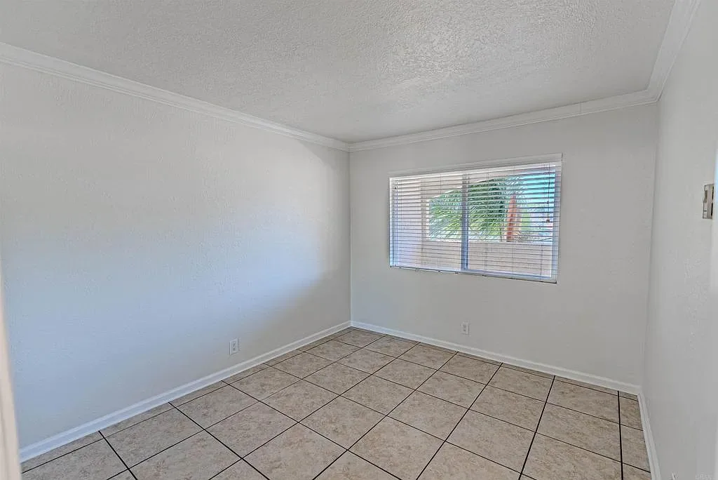 Second bedroom with ceramic tile flooring and crown molding at 1085 12th St Unit F