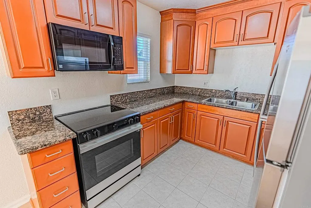 Kitchen with wood cabinetry and granite counters at 1085 12th St Unit F