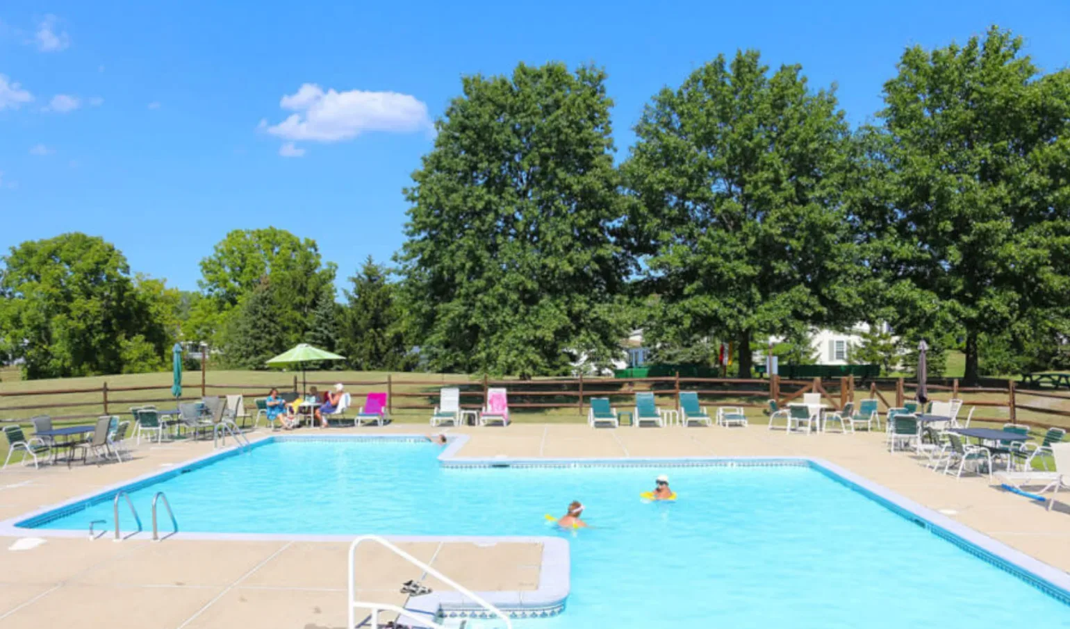 Community clubhouse with a pool, a pond, and shade trees at an active adult community in suburban Pennsylvania
