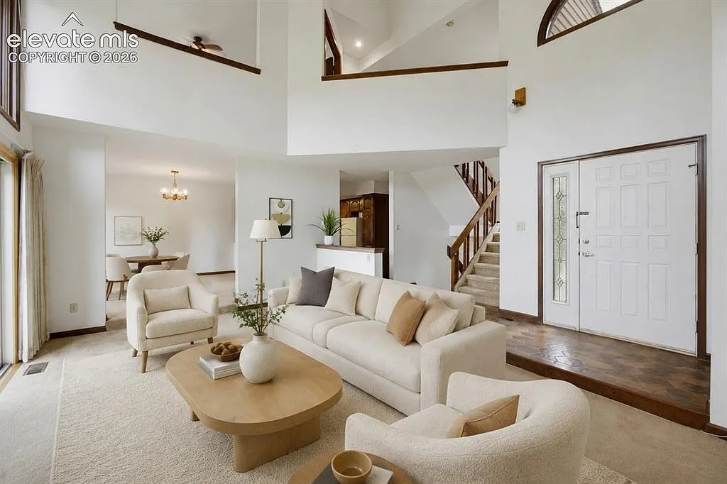 Vaulted living room and entryway with wood staircase