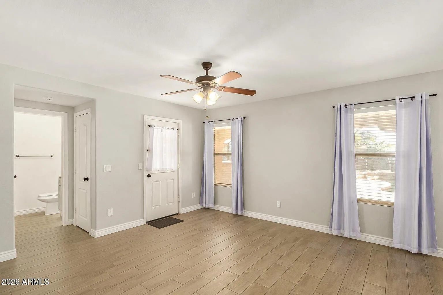 Open living room with wood-look tile flooring and tall windows