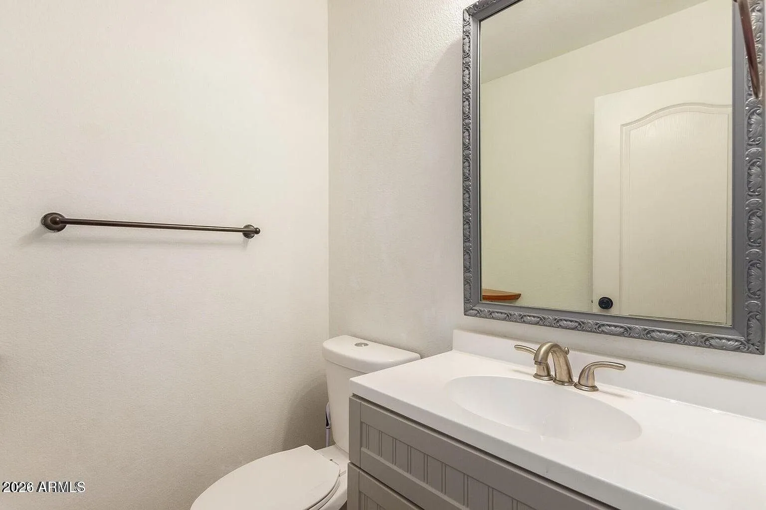 Half bathroom with gray vanity and silver mirror