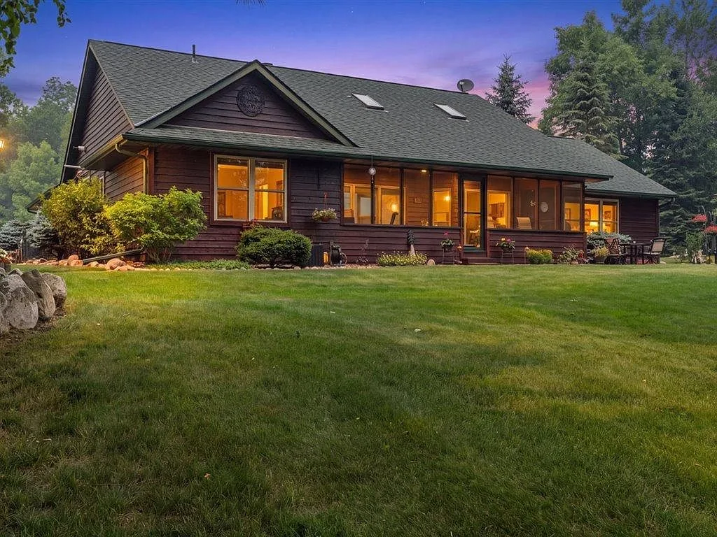 Dusk view of the lakeside facade with the screened porch lit from inside