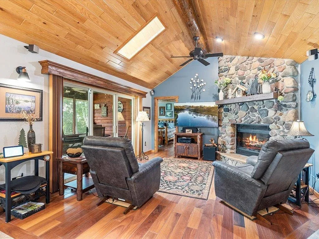 Living room with a vaulted wood ceiling, skylight, and a fieldstone fireplace