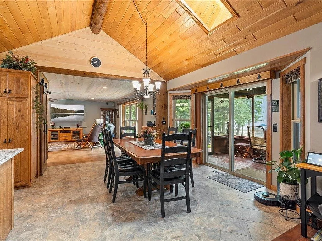 Dining room open to the living room beneath vaulted wood ceilings