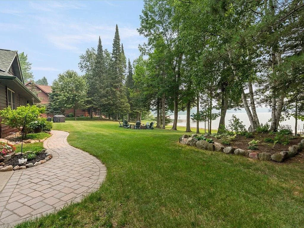 Stone paver walkway, lawn, and lake view at the back of the home