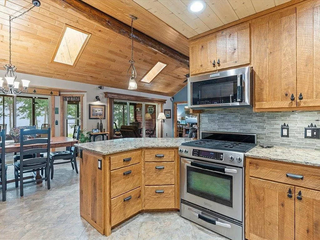 Kitchen view toward the dining area with stone backsplash and skylights