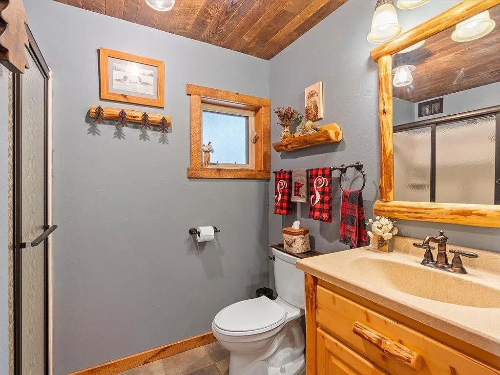 Bathroom with tongue-and-groove ceiling and log-frame mirror
