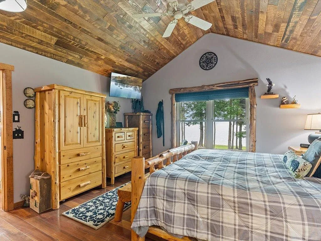 Primary bedroom with reclaimed wood ceiling and lake views through the windows