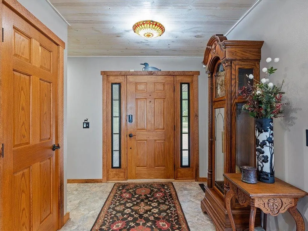 Home entryway with natural wood door, tile floor, and wood-paneled ceiling