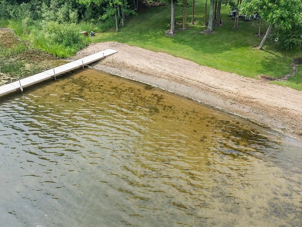 Aerial view of the private sandy beach and wooden dock at the Mitchell Lake shoreline