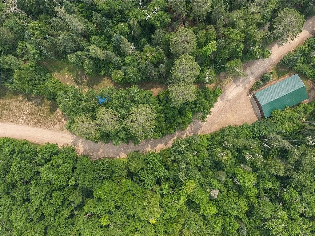 Aerial view of the 30x60 detached shop with a green metal roof set in a wooded lot