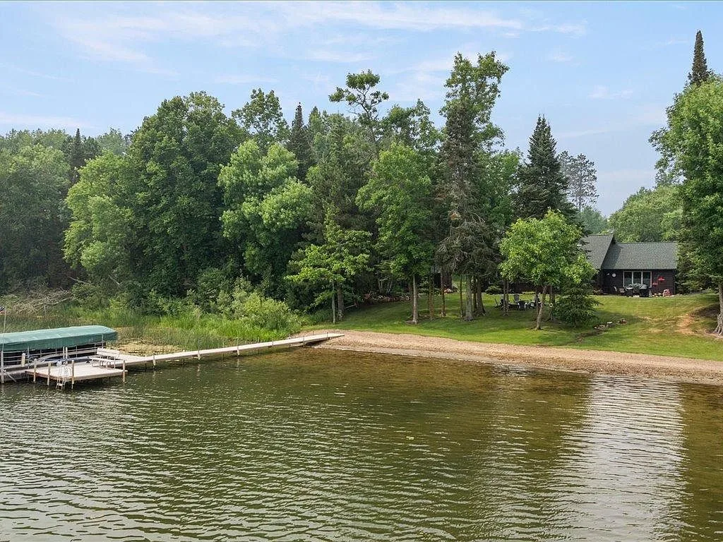 Lakefront shoreline with a covered boat slip and mature trees