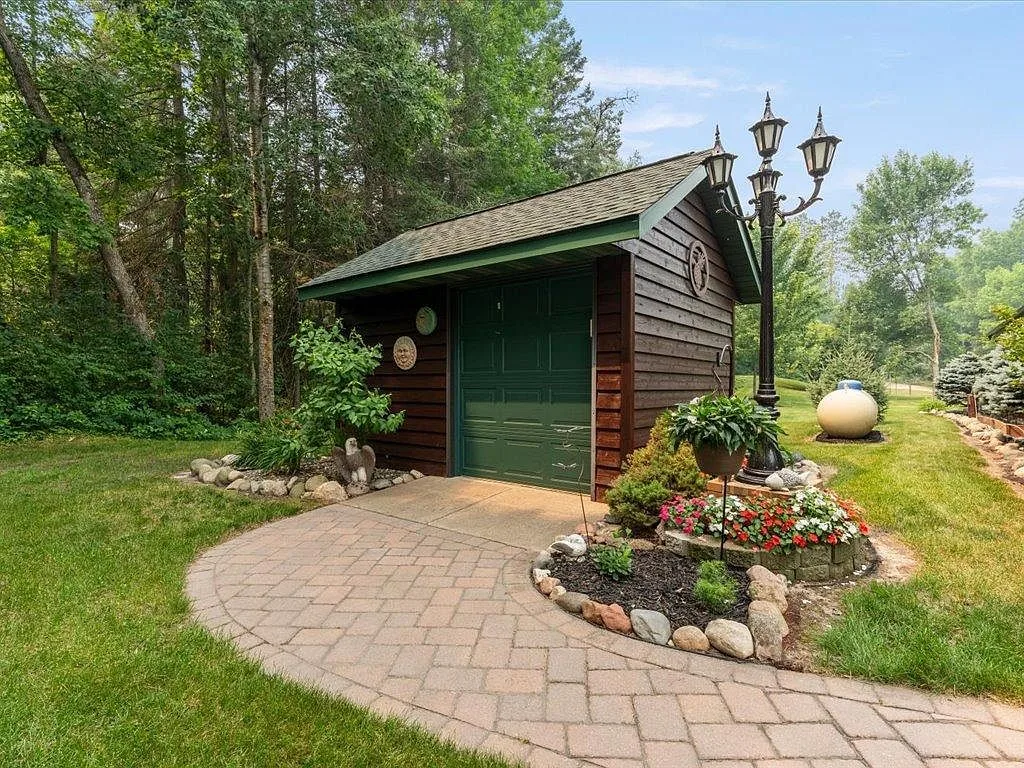 Lakeside storage building with green trim and a stone walkway