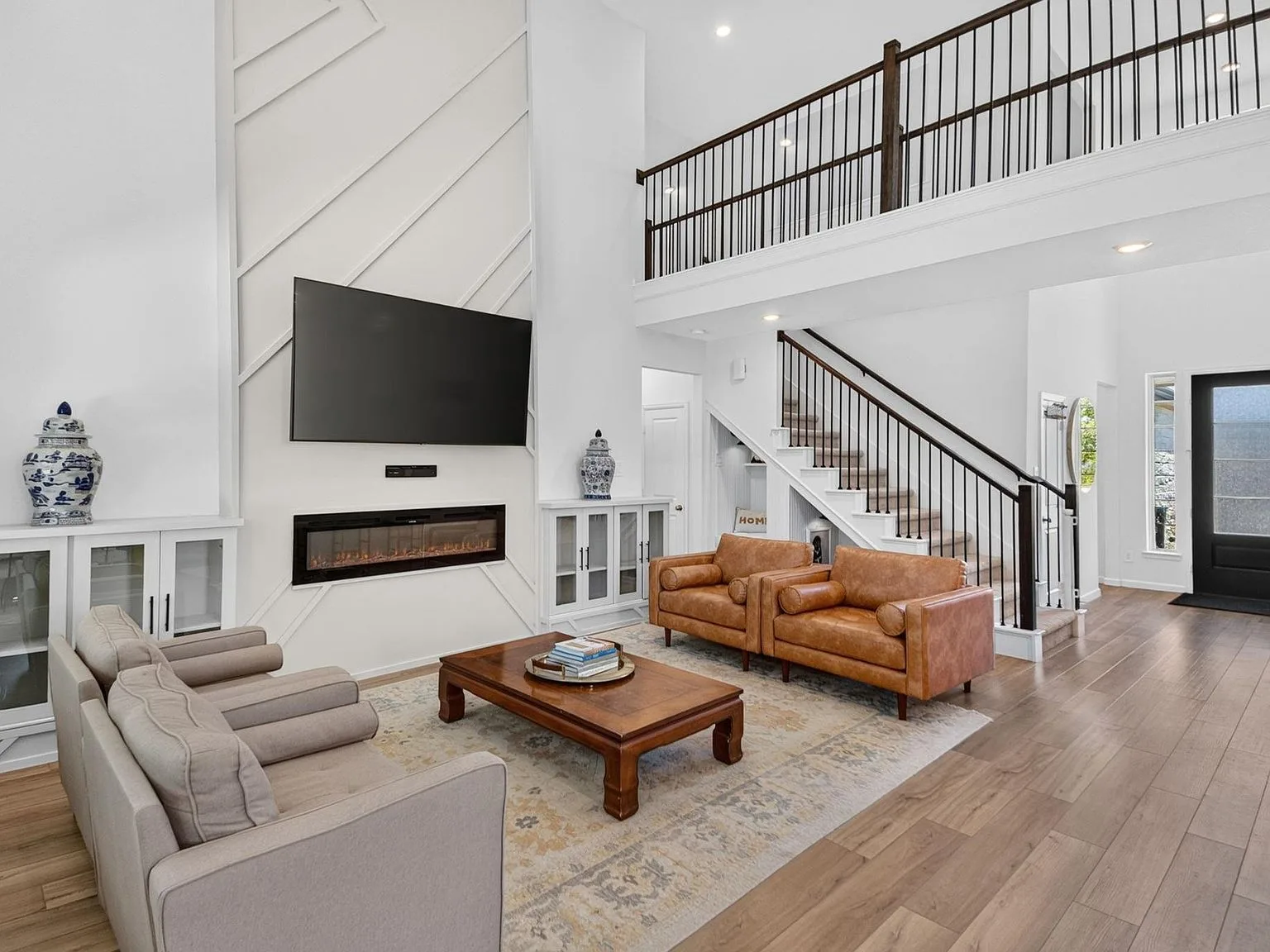 Two-story great room with vaulted ceiling, open loft railing, fireplace, and hardwood floors