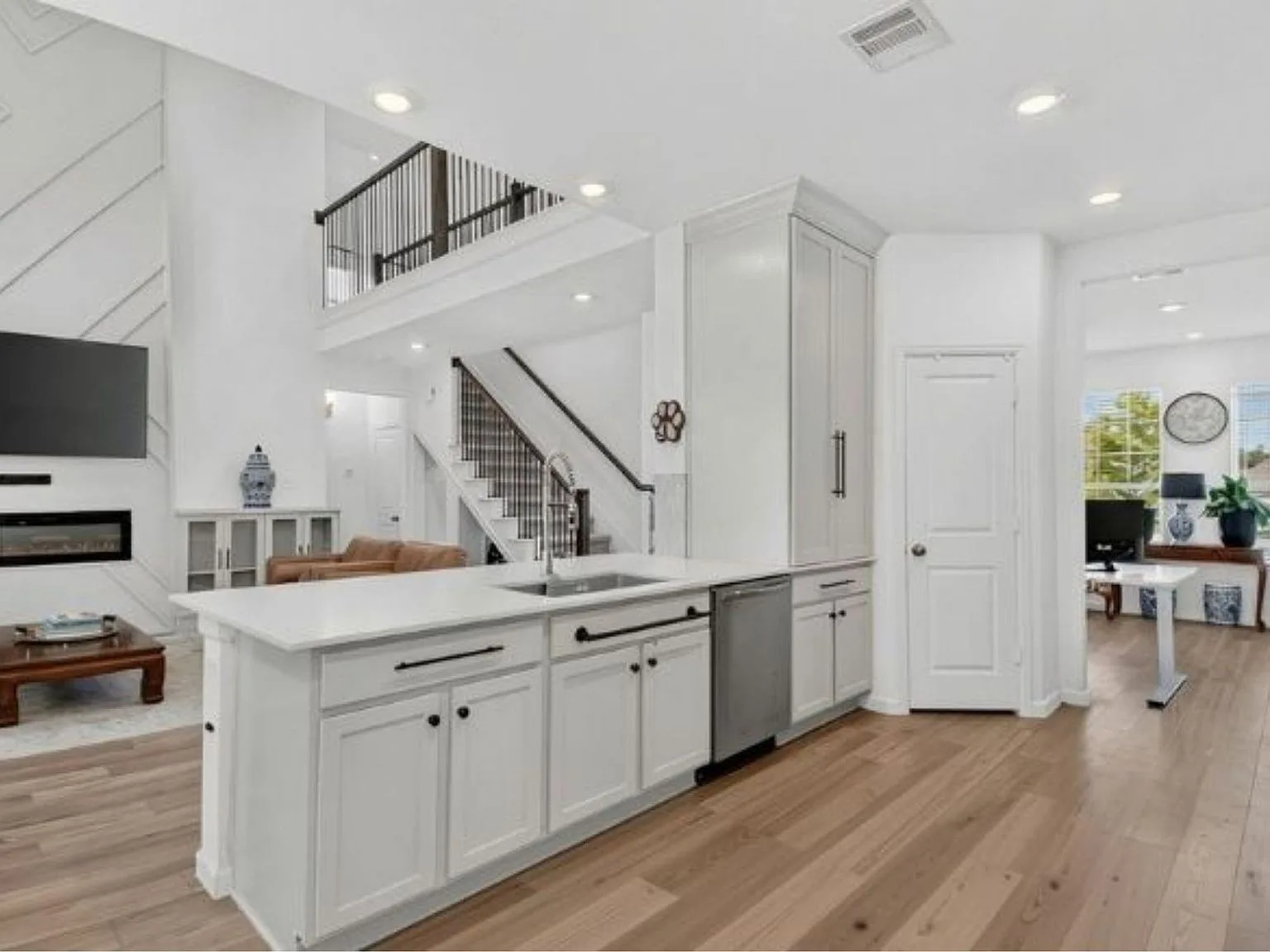 Open-concept kitchen and living space with an island, 18-foot ceilings, and a stairway with iron railing