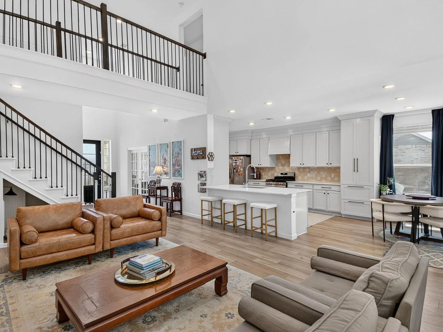 Open-concept great room flowing into the kitchen with a second-floor mezzanine and iron railings