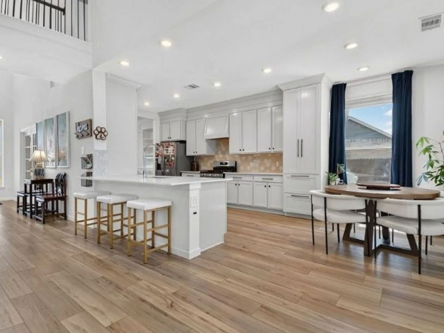 Kitchen and dining area with an island, stone backsplash, and waterfall countertop