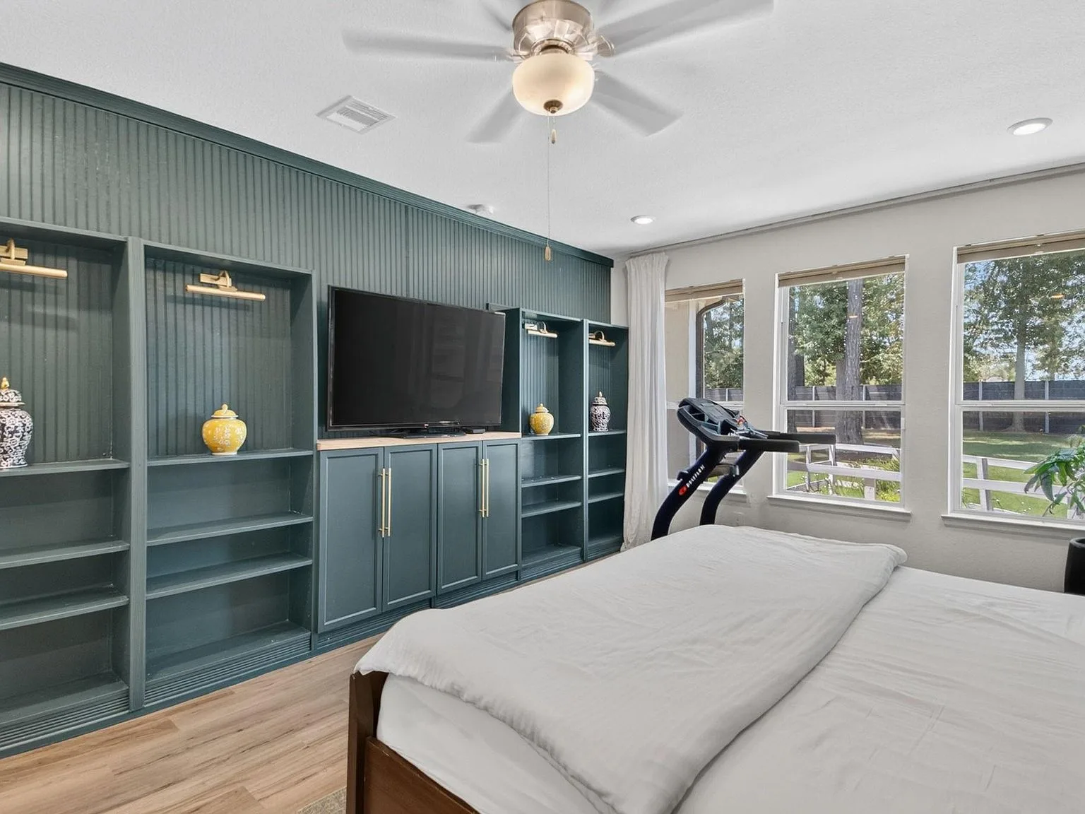 Primary bedroom with a custom teal wall unit of shelving and cabinetry