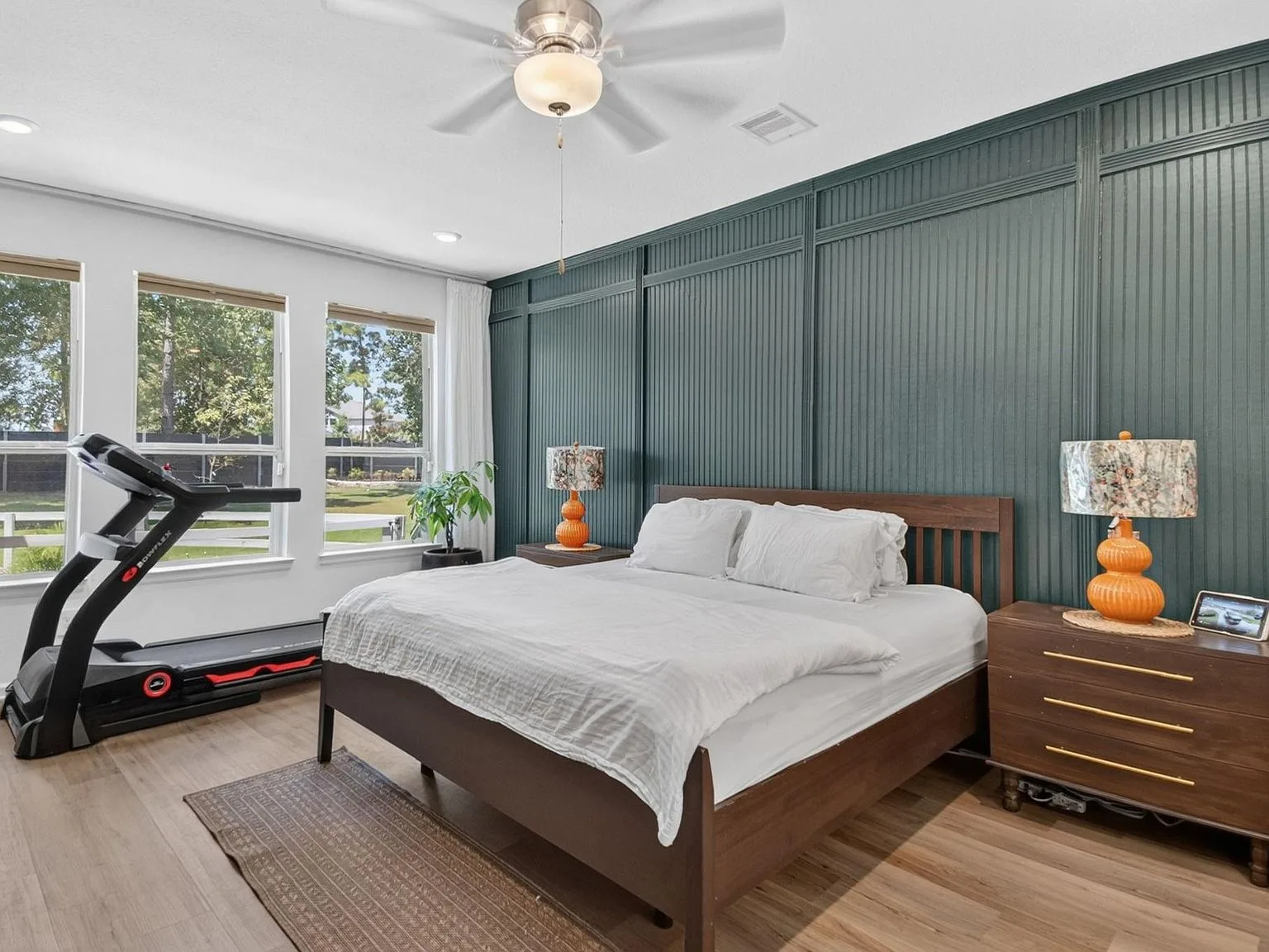 Primary bedroom with a dark green vertical beadboard accent wall and light wood flooring