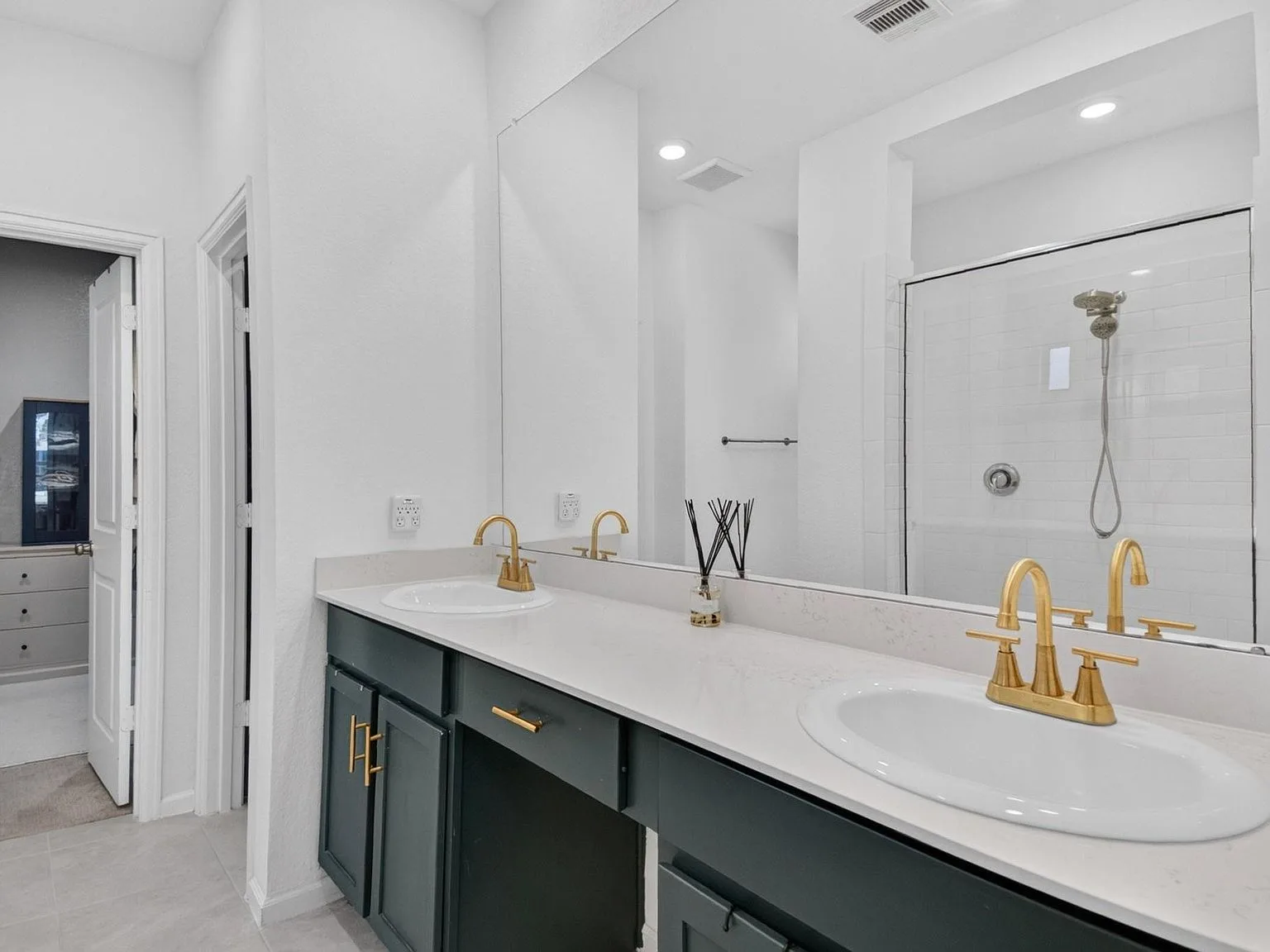 Primary bathroom vanity with white quartz, forest green cabinets, and gold-toned fixtures
