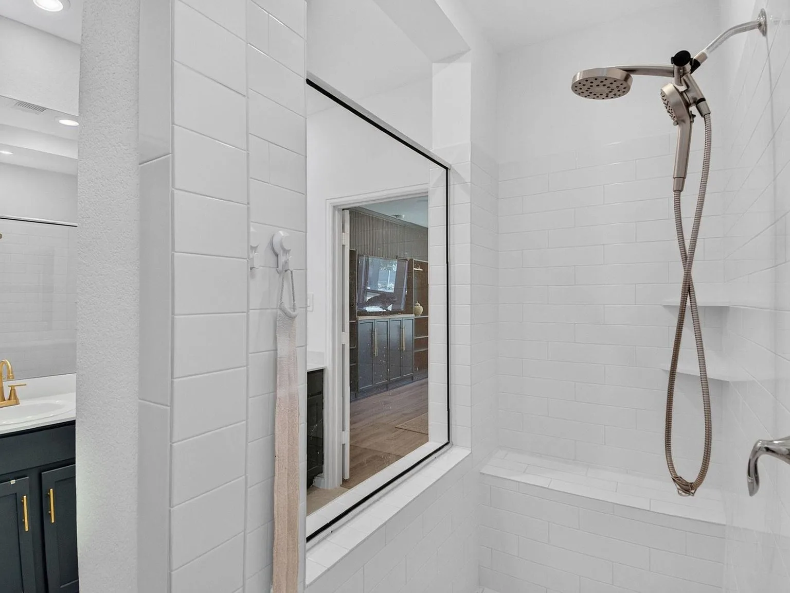 Tiled primary shower stall with white subway tile and a built-in bench
