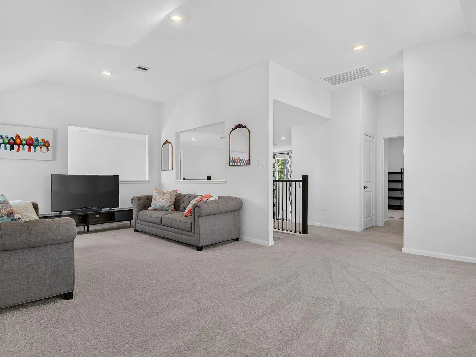 Upstairs living and media room with neutral carpet and recessed lighting