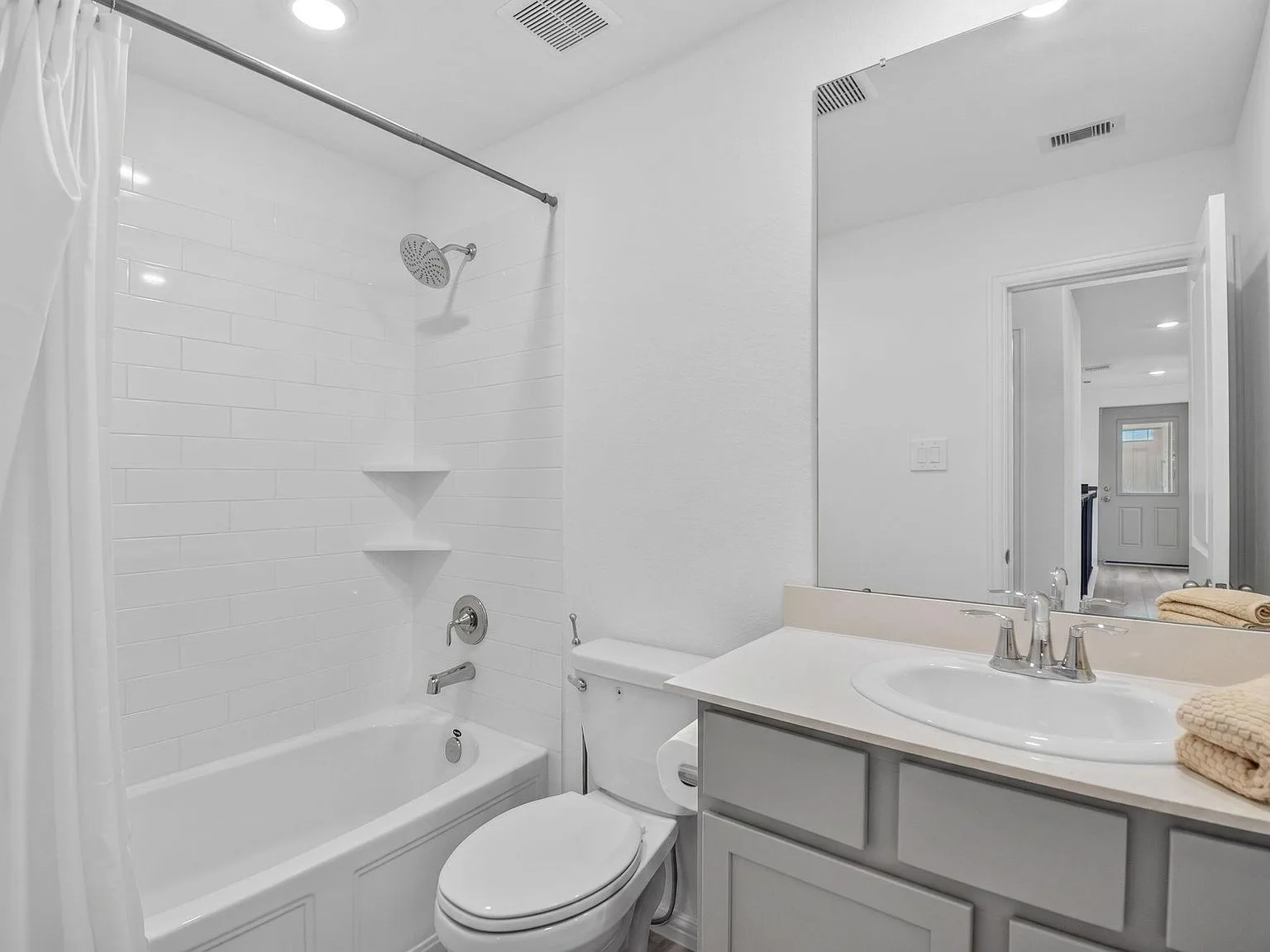 Guest bathroom with gray vanity, white counter, and a tiled shower-tub combo