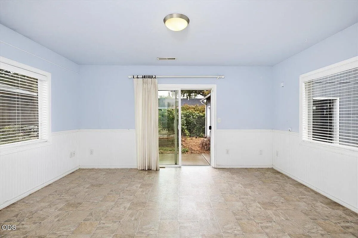 Living room facing a sliding glass door that opens to the backyard, with white wainscoting