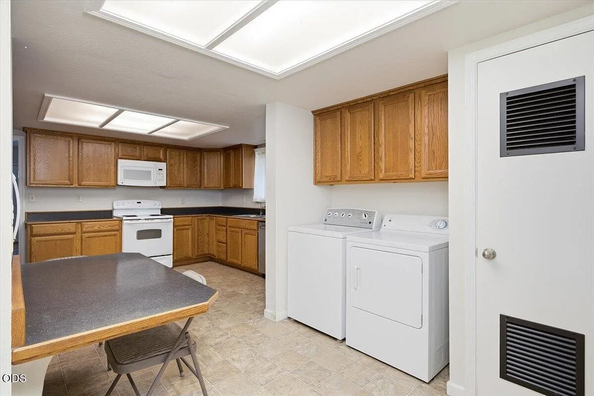 Kitchen laundry corner with white appliances and oak cabinetry