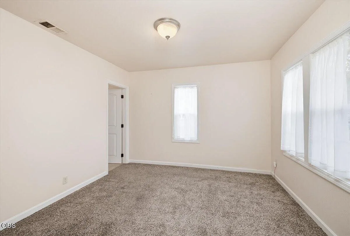 Primary bedroom with neutral paint, carpet, and windows with sheer curtains