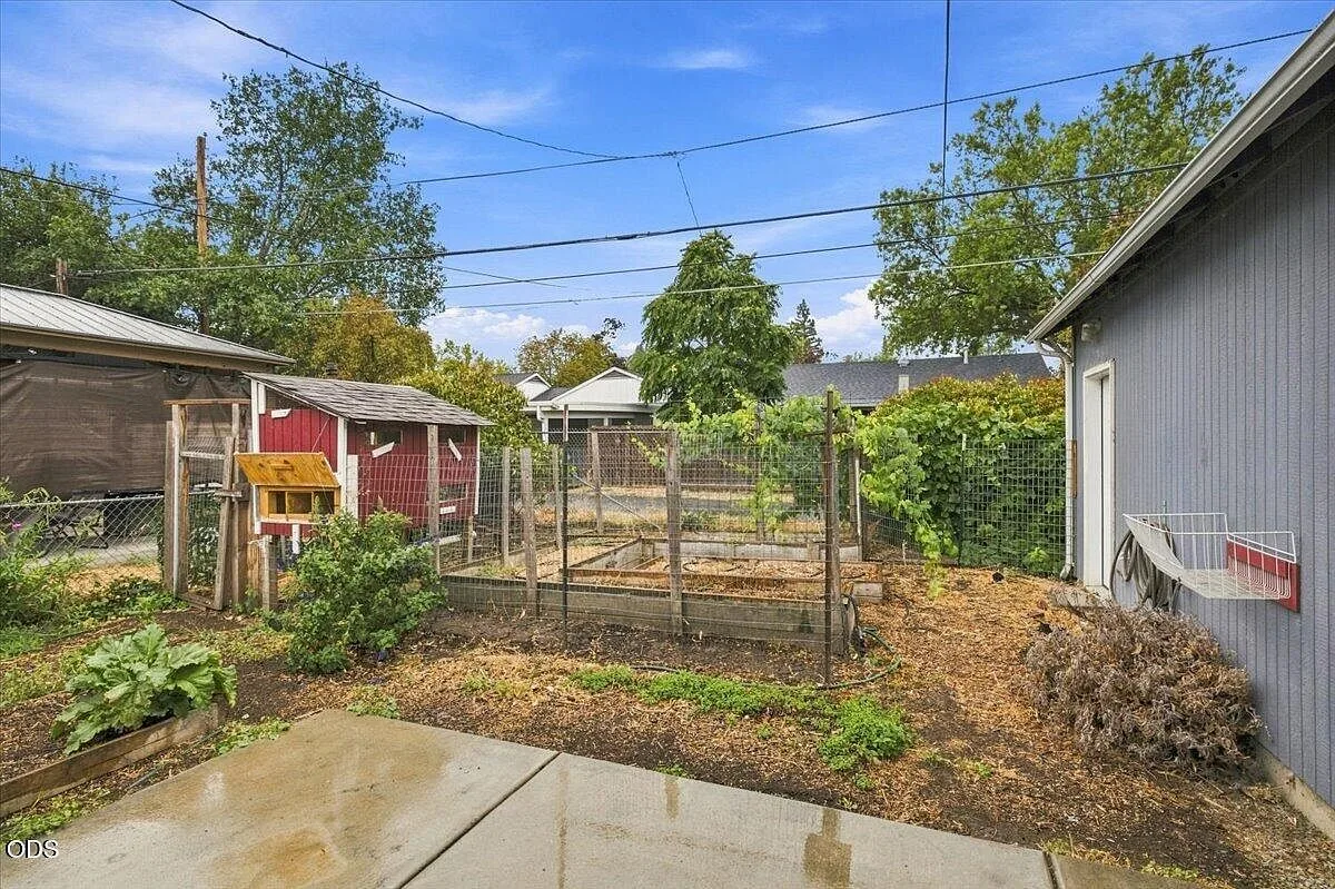 Fenced backyard with raised garden beds, a garden shed, and a concrete patio