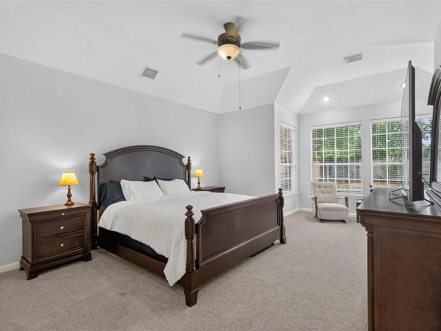 Primary bedroom with vaulted ceilings and neutral finishes