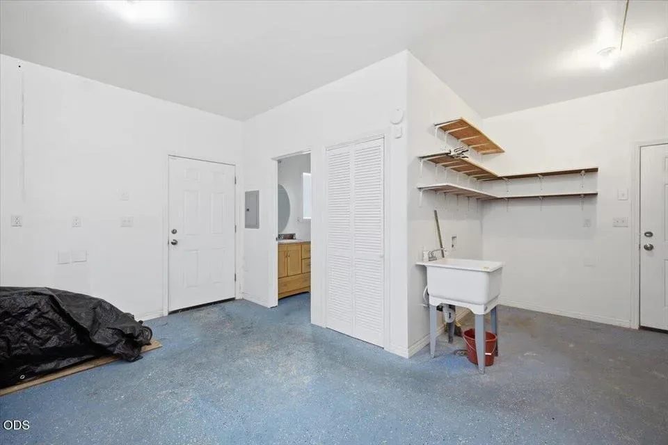 Utility flex space inside the detached storage building with a white utility sink and a door to the small full bath