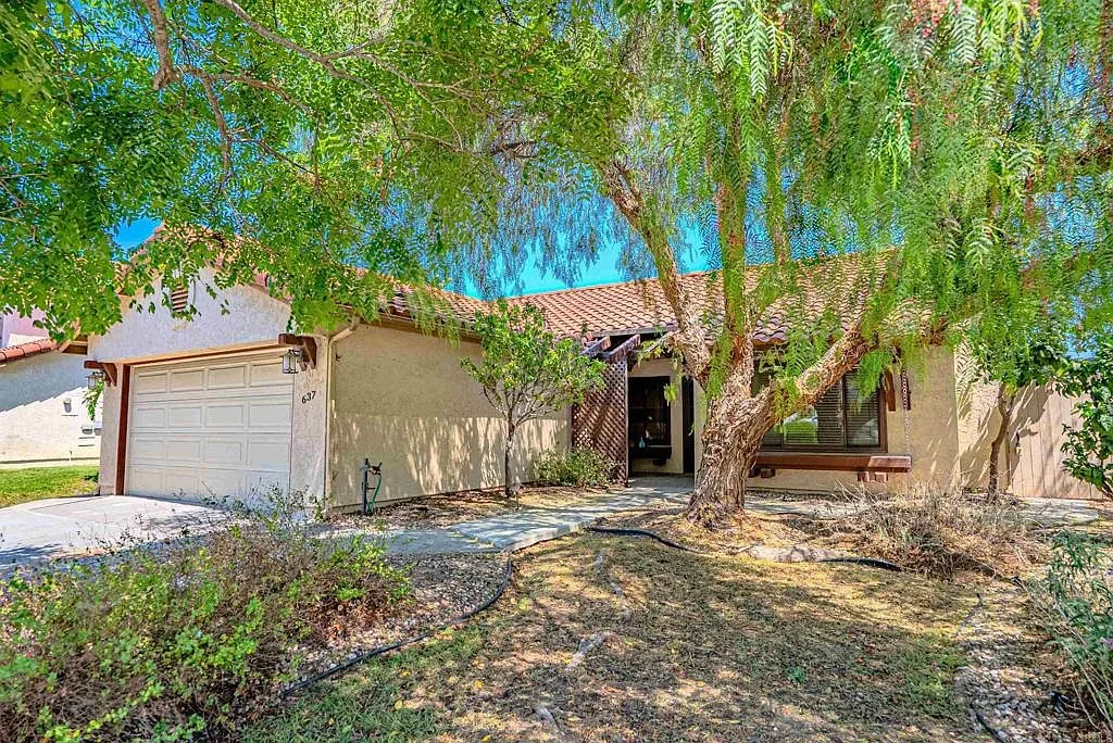 Front facade of 637 Redlands Pl, a single-story stucco home with a tile roof behind mature trees in Bonita, California